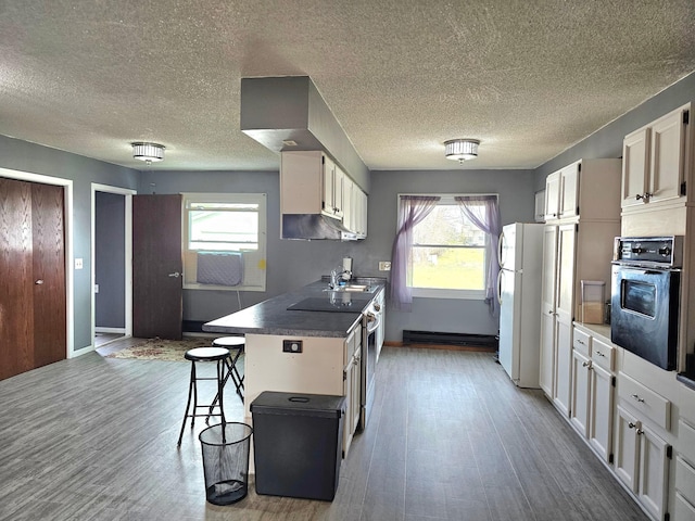 kitchen featuring white cabinetry, a breakfast bar, oven, and white fridge