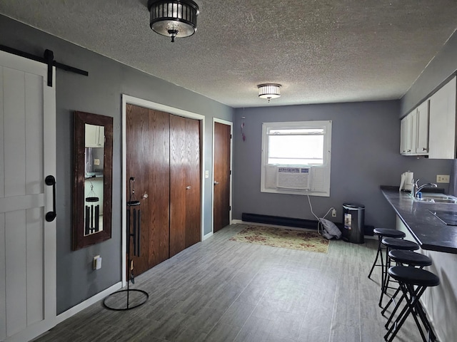 interior space with a textured ceiling, cooling unit, sink, a barn door, and light hardwood / wood-style floors