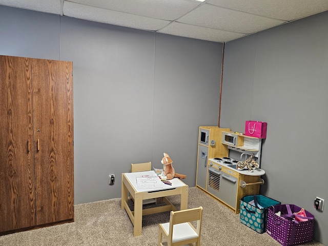 recreation room featuring carpet and a drop ceiling