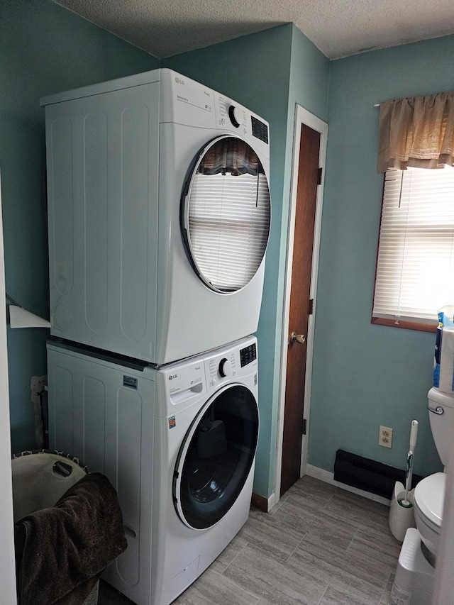 laundry area featuring stacked washer / drying machine and a textured ceiling