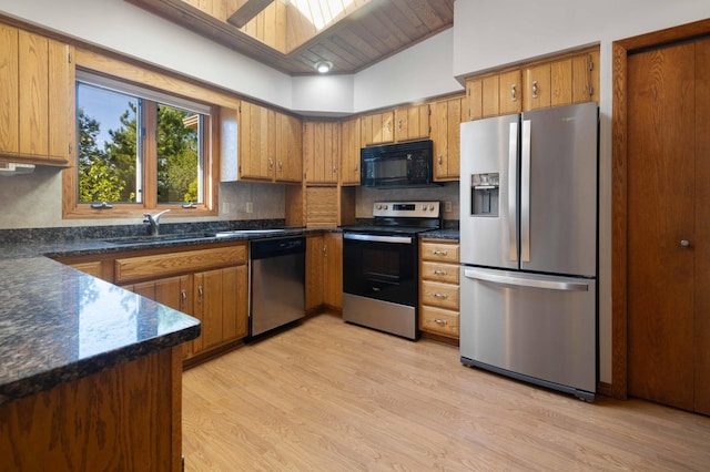 kitchen featuring sink, wooden ceiling, vaulted ceiling with skylight, light wood-type flooring, and appliances with stainless steel finishes