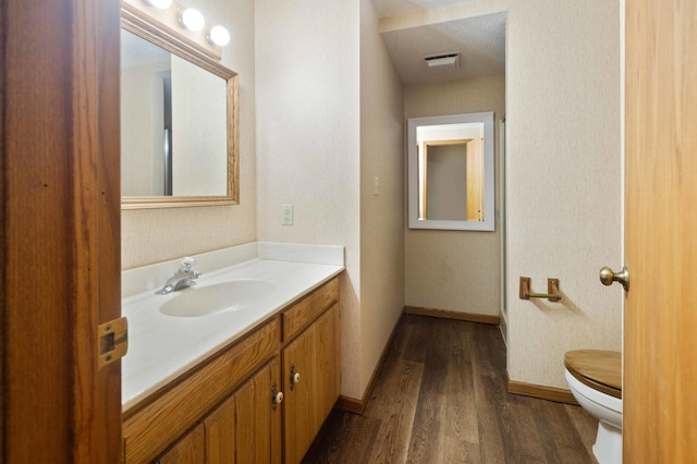 bathroom with hardwood / wood-style floors, vanity, toilet, and a textured ceiling