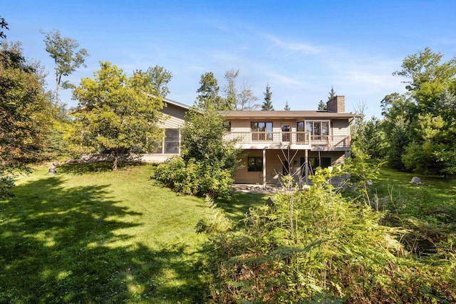 back of house featuring a balcony and a lawn