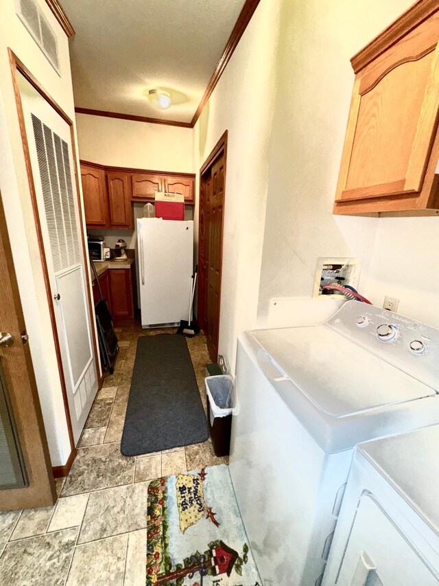 clothes washing area featuring cabinets, ornamental molding, a textured ceiling, and independent washer and dryer