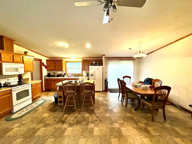 kitchen featuring ornamental molding, a center island, a breakfast bar area, white appliances, and ceiling fan with notable chandelier