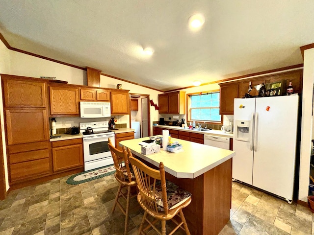 kitchen with washer / dryer, a kitchen island, a kitchen breakfast bar, white appliances, and lofted ceiling