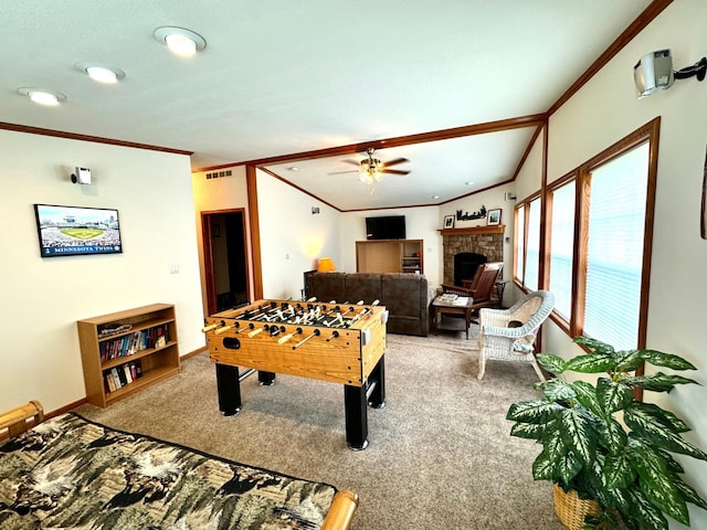 rec room with carpet, a fireplace, ceiling fan, and crown molding