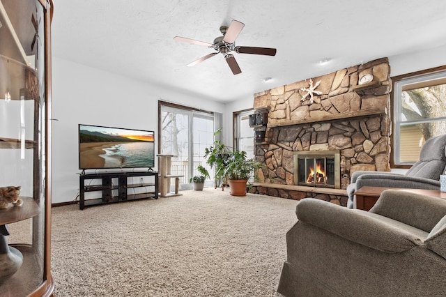 carpeted living room with ceiling fan, a textured ceiling, and a fireplace