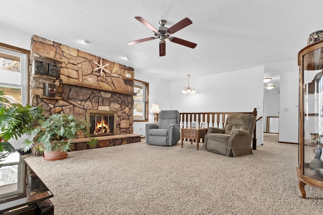 carpeted living room featuring ceiling fan, a stone fireplace, and a textured ceiling