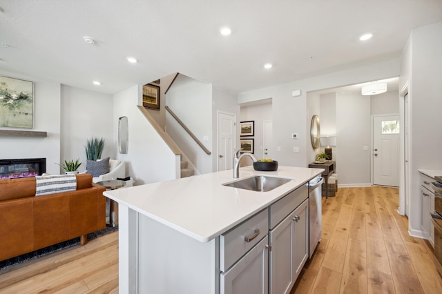 kitchen featuring an island with sink, light hardwood / wood-style flooring, sink, and dishwasher