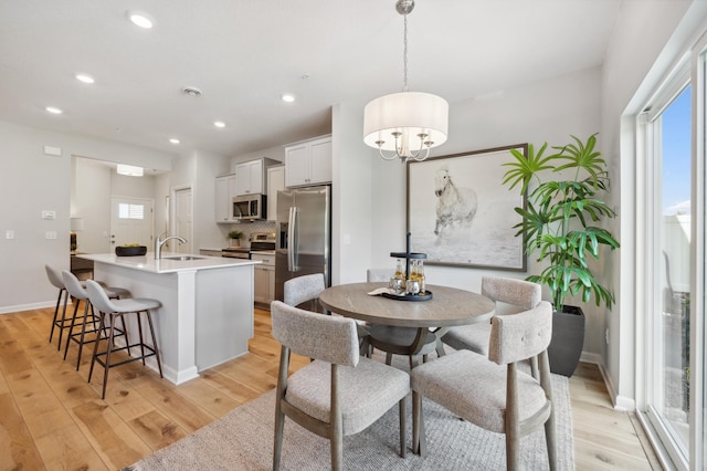 dining room with an inviting chandelier, light hardwood / wood-style floors, and sink