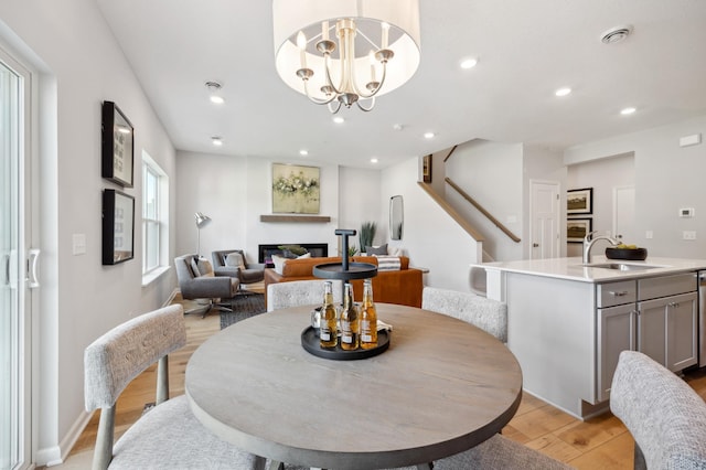 dining space with a fireplace, light wood-type flooring, sink, and a healthy amount of sunlight