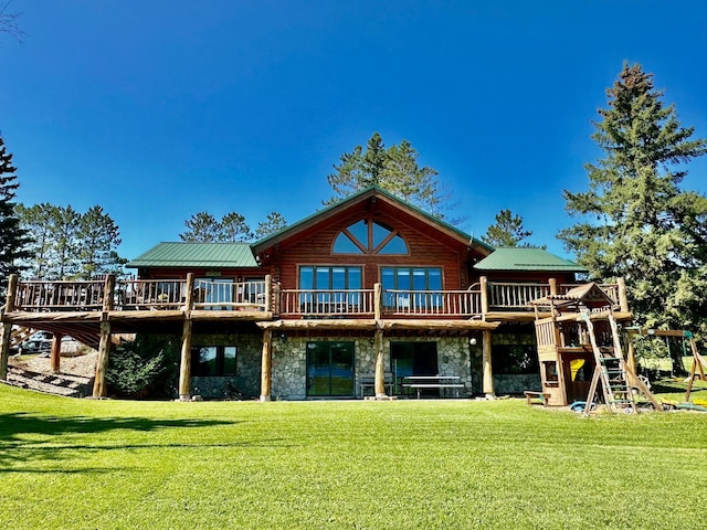 rear view of house with a lawn, a deck, and a playground