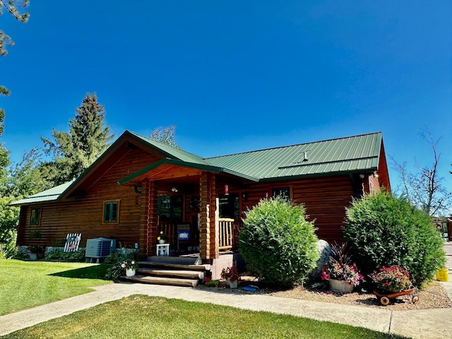 log home with cooling unit, a porch, and a front yard