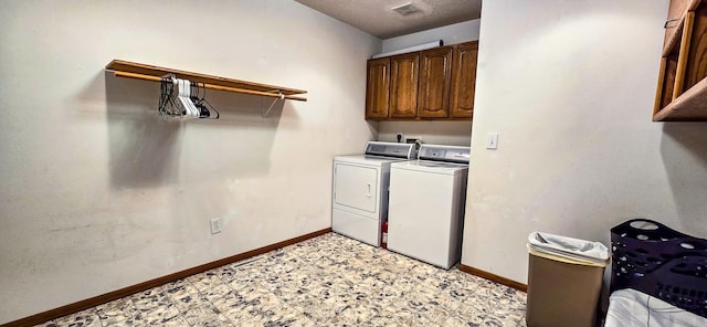 laundry room with a textured ceiling, cabinets, and washing machine and clothes dryer