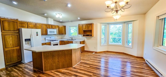 kitchen featuring vaulted ceiling, plenty of natural light, baseboard heating, a center island, and white appliances