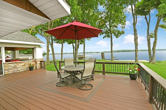 wooden terrace with outdoor dining space, a lawn, and a water view