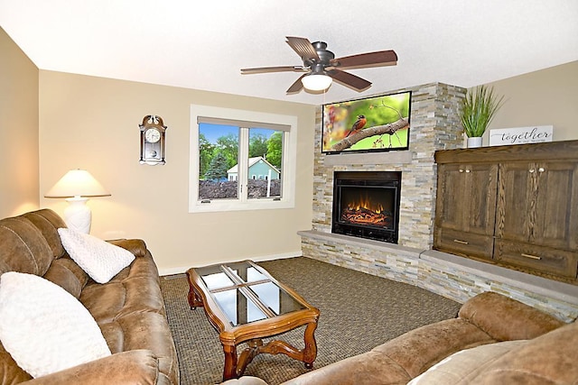 living area featuring carpet flooring, ceiling fan, a stone fireplace, and baseboards