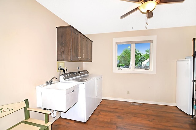 washroom with a sink, baseboards, washer and dryer, cabinet space, and dark wood-style floors