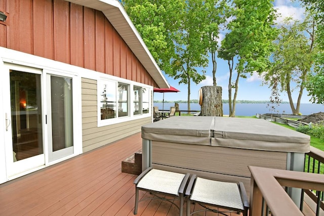 deck with a water view and a hot tub