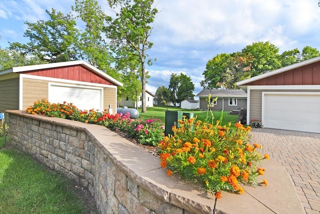 view of yard with a garage, an outbuilding, and driveway