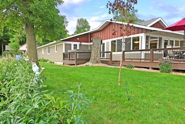 back of property with a deck, a yard, and board and batten siding