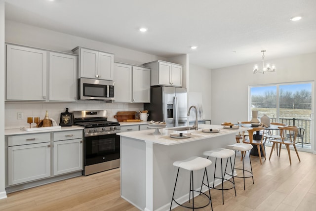 kitchen featuring a center island with sink, light hardwood / wood-style floors, sink, and appliances with stainless steel finishes