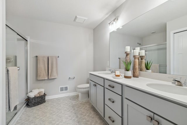 bathroom featuring vanity, toilet, and a shower with shower door