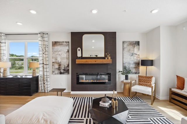 living room with a large fireplace, wood finished floors, and recessed lighting