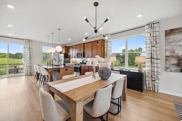 dining space with a healthy amount of sunlight, sink, and light hardwood / wood-style flooring