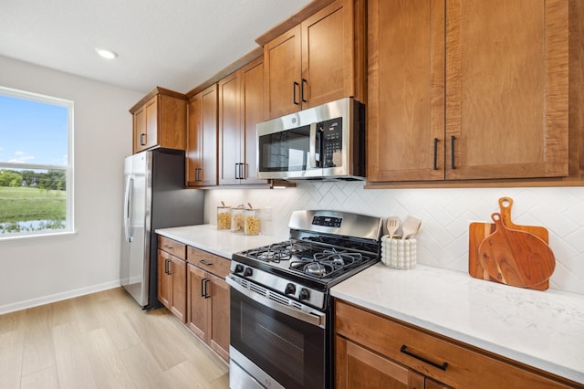 kitchen featuring stainless steel appliances, decorative backsplash, and light hardwood / wood-style flooring