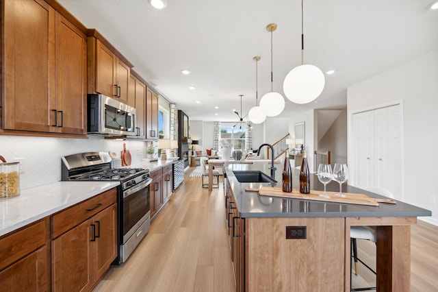 kitchen featuring light hardwood / wood-style floors, appliances with stainless steel finishes, a center island with sink, and sink