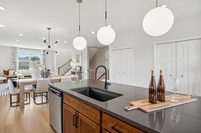 kitchen with pendant lighting, light hardwood / wood-style flooring, a notable chandelier, stainless steel dishwasher, and sink