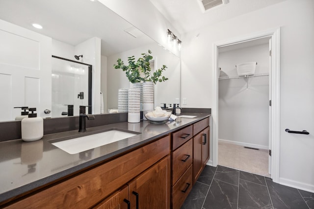 bathroom featuring a shower with door and vanity