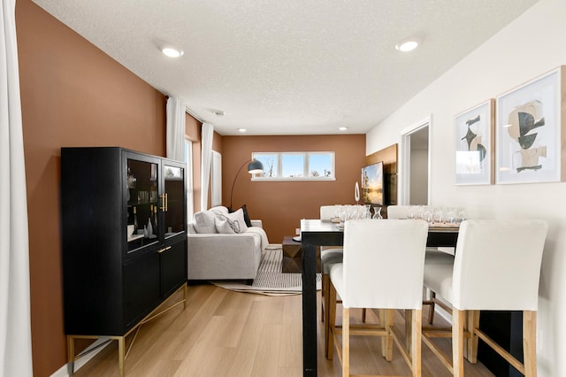 dining room featuring light wood-type flooring and a textured ceiling