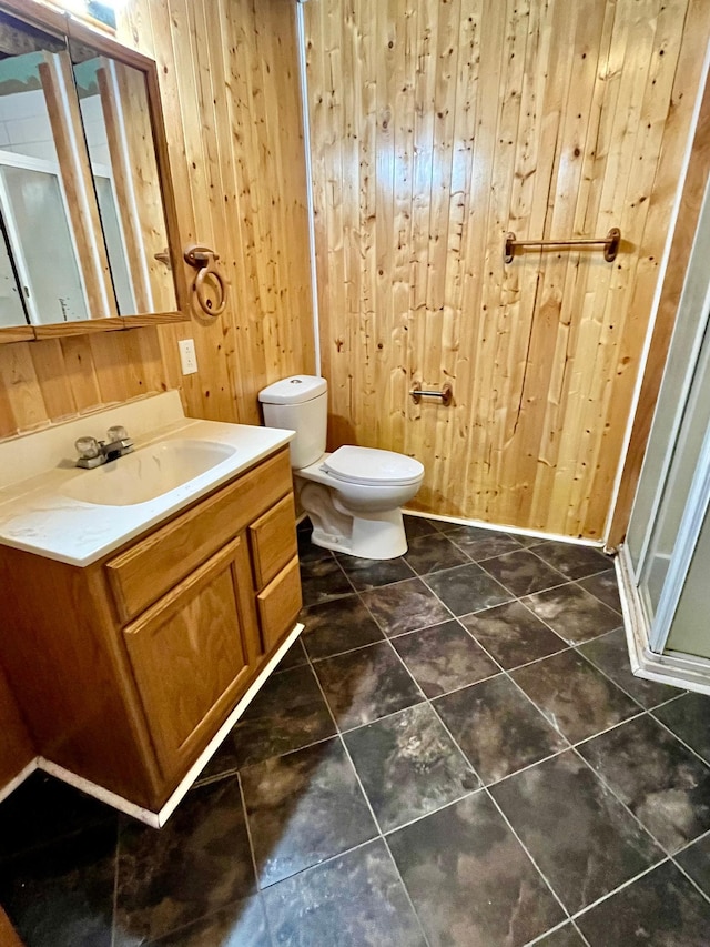 bathroom with tile patterned flooring, wooden walls, walk in shower, vanity, and toilet