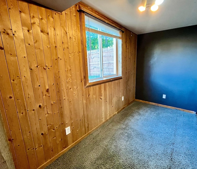 carpeted spare room featuring wood walls