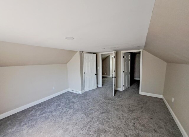 additional living space with vaulted ceiling and dark carpet