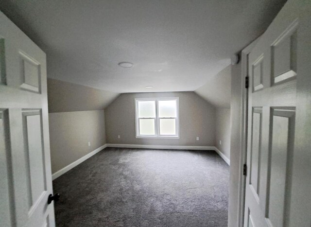 bonus room featuring lofted ceiling, dark colored carpet, and a textured ceiling