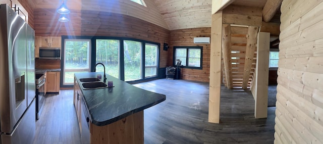 kitchen featuring a wall mounted AC, hardwood / wood-style floors, appliances with stainless steel finishes, an island with sink, and sink