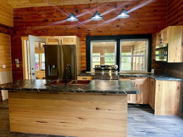 kitchen featuring appliances with stainless steel finishes, light brown cabinetry, wood-type flooring, and hanging light fixtures