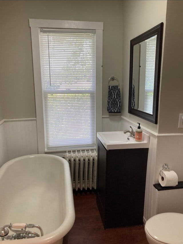 bathroom featuring toilet, hardwood / wood-style flooring, radiator heating unit, vanity, and a bathing tub