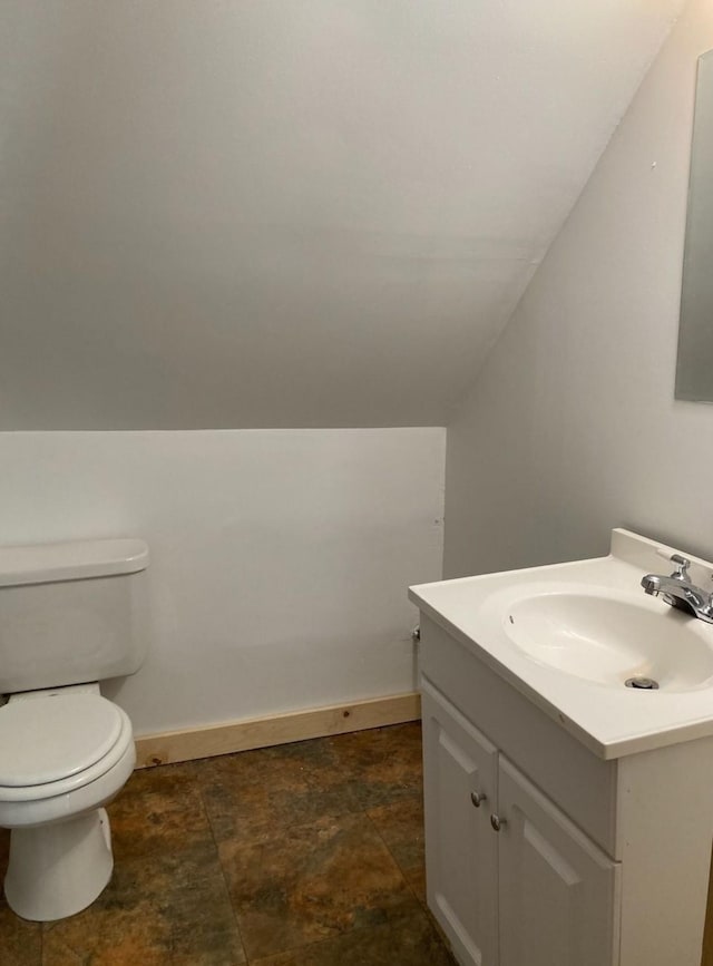 bathroom with lofted ceiling, vanity, and toilet