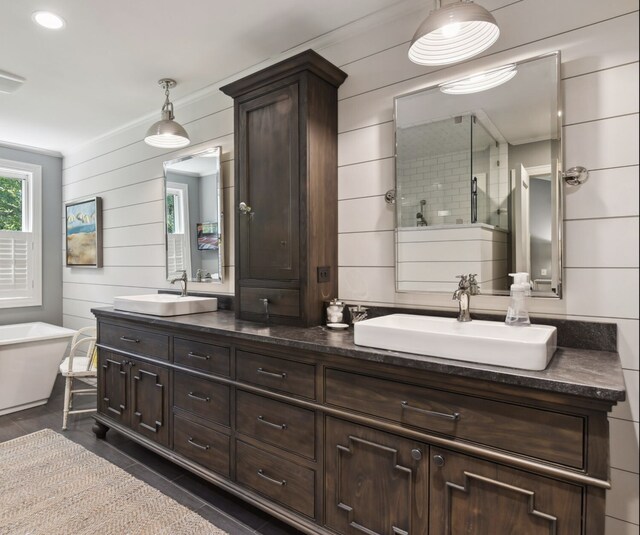 full bath featuring double vanity, a soaking tub, walk in shower, and a sink