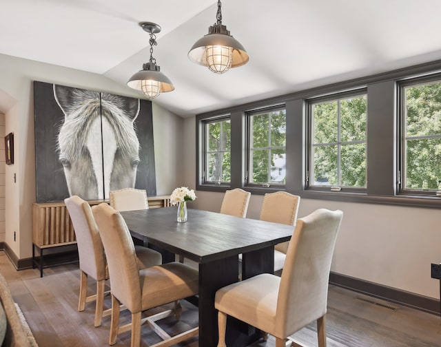 dining room featuring visible vents, lofted ceiling, baseboards, and wood finished floors