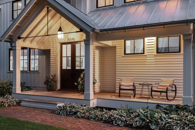 entrance to property featuring a porch, metal roof, a standing seam roof, and board and batten siding