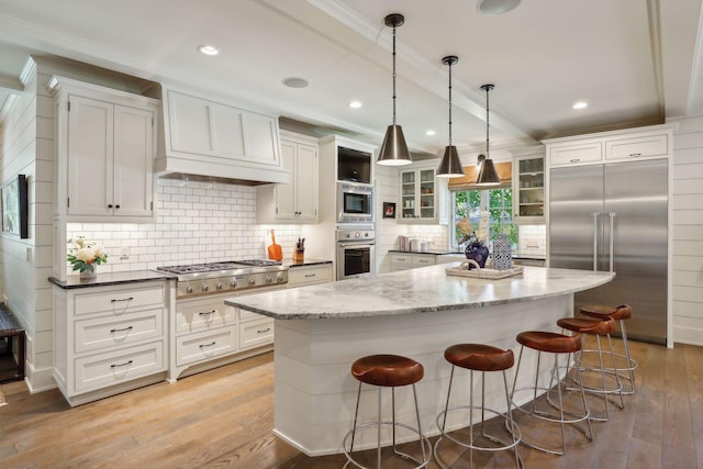 kitchen featuring light wood finished floors, built in appliances, white cabinetry, and glass insert cabinets