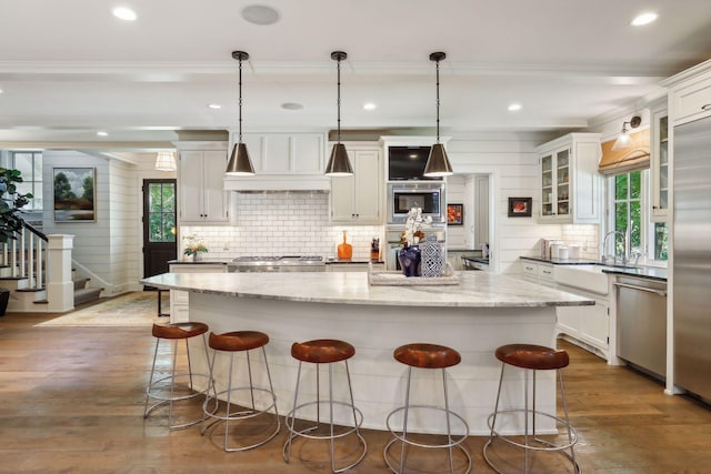 kitchen featuring a kitchen breakfast bar, backsplash, dark wood-style floors, white cabinets, and built in appliances