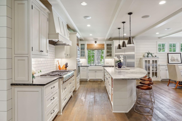 kitchen featuring a kitchen bar, wood-type flooring, appliances with stainless steel finishes, and ornamental molding