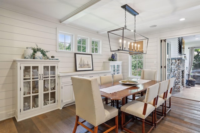 dining room featuring a notable chandelier, wooden walls, dark hardwood / wood-style flooring, and a wealth of natural light